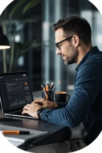 Man typing on laptop with analytics charts in office